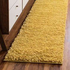 a long yellow rug is on the floor in front of a white cabinet and drawers