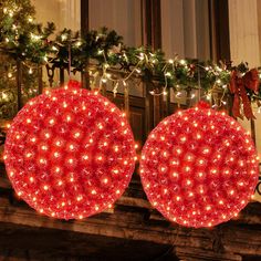 two lighted christmas ornaments on a mantel