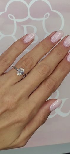 a woman's hand with pink manicured nails and a diamond ring