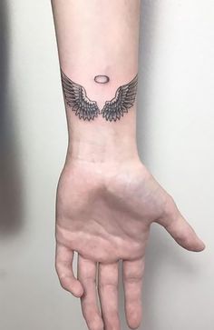 a person's hand with a small tattoo on the wrist and an angel wing