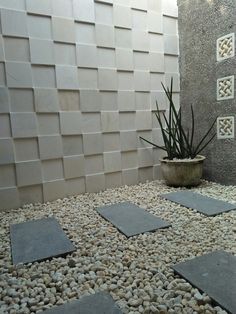 an outdoor shower with rocks and plants in the corner, next to a tiled wall