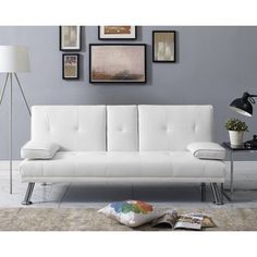 a white futon sofa sitting on top of a rug next to a table and lamp