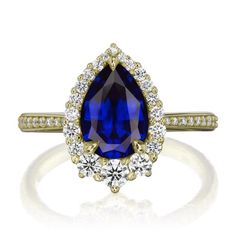 a blue sapphire and diamond ring with two diamonds on the side, set in yellow gold