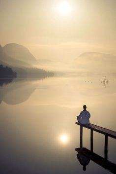 a man sitting on a dock looking out at the water