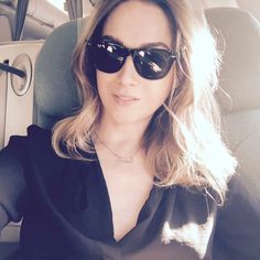 a woman sitting in the back seat of a car wearing sunglasses and a black shirt