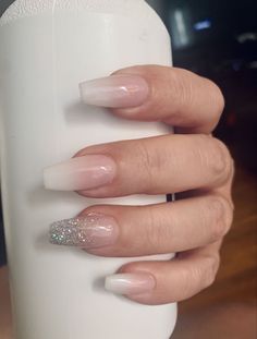 a woman's hand holding a white bottle with some glitter on top of it