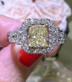 a yellow diamond ring sitting on top of a woman's hand next to a white rose