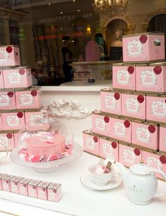 there is a pink cake on display in the store window with other items around it