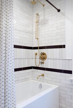 a white bath tub sitting next to a shower with black and white tiles on the walls