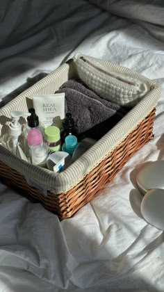 a wicker basket filled with personal care items on top of a white sheeted bed