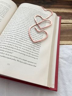 an open book with a metal heart on it's cover sitting on a table