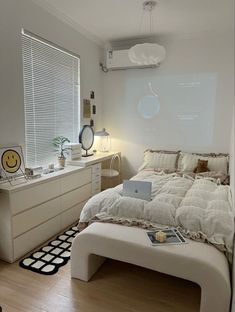 a bed room with a neatly made bed and a laptop computer on the desk next to it