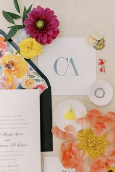 the wedding stationery is laid out on top of the table with flowers and rings