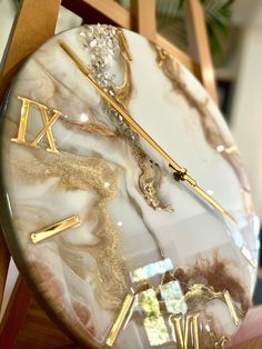 a marble clock with gold hands and roman numerals on the face is sitting on a wooden chair