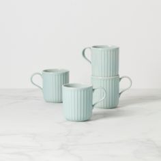 three green mugs sitting on top of a white marble countertop next to each other