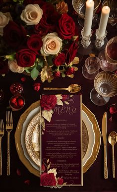 the table is set with red roses and gold place settings for an elegant dinner party