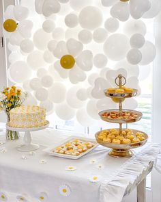 a table topped with cakes and desserts under balloons