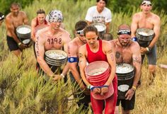 a group of men and women carrying buckets full of food on their backs while standing in tall grass