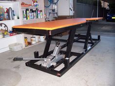 a workbench in a garage with tools on the floor and shelves behind it