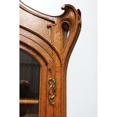 an ornate wooden mirror frame with brass accents on the top and bottom part, in front of a white wall