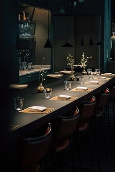 a long table with place settings and wine glasses on it in a dimly lit room