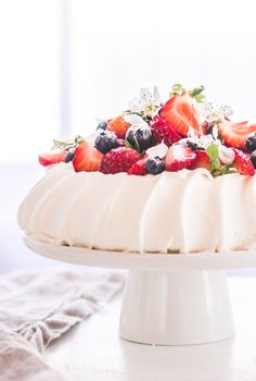 a white cake topped with fresh berries and whipped cream