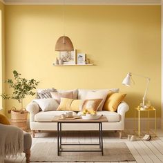 a living room with yellow walls, white furniture and rugs on the wooden floor