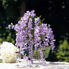 purple and white flowers in vases sitting on a table with silverware next to it