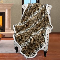 a leopard print blanket sitting on top of a white chair in front of a fireplace