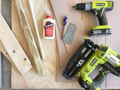 some tools are laying out on a wooden table next to wood planks and glue