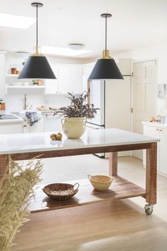 a kitchen with white cabinets and black pendant lights hanging from the ceiling over an island