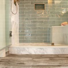 a bathroom with a walk in shower next to a tiled wall and wooden flooring