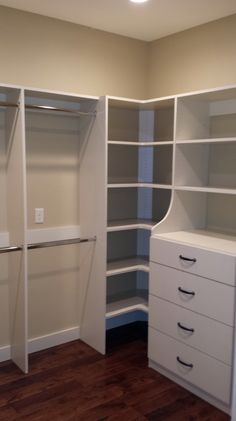 an empty walk in closet with white shelves and drawers