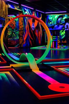 an indoor trampoline course with colorful lights and art on the walls behind it