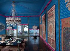 a dining room with blue walls and chandelier hanging from the ceiling in front of windows