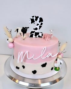 a pink cake with black and white cow decorations