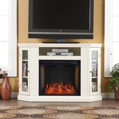 a flat screen tv mounted on top of a white entertainment center with an open fire place