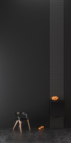 a black chair sitting in front of a wall with oranges on the floor next to it