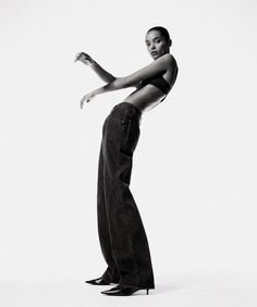 a black and white photo of a woman in high - rise jeans with her arms outstretched