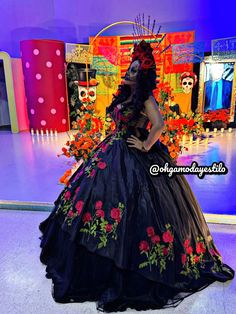 a woman in a black dress with red flowers on the skirt and headpieces