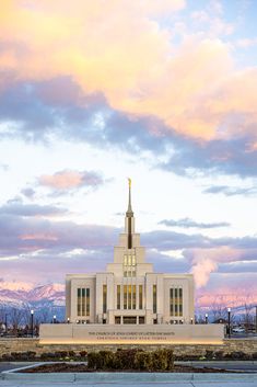 a large white building with a steeple on it's side and mountains in the background