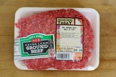 ground beef is shown in a plastic container on a wooden table with the label for ground beef