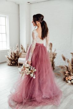 a woman in a long pink dress is standing on the floor with her back to the camera