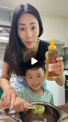 a woman and child are cooking together in the kitchen, one is holding a bottle of oil while the other holds a spoon