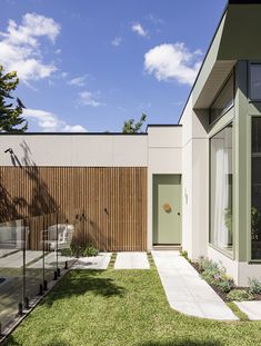 a modern house with green doors and windows