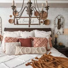 a bed with many pillows on it and a chandelier hanging above the headboard