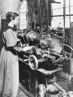 an old black and white photo of a woman working on a machine