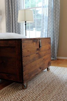 a bed sitting on top of a wooden box next to a window with blue curtains