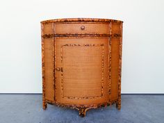 an old wicker cabinet sitting on the floor in front of a white wall,