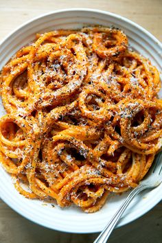 a white bowl filled with pasta on top of a wooden table